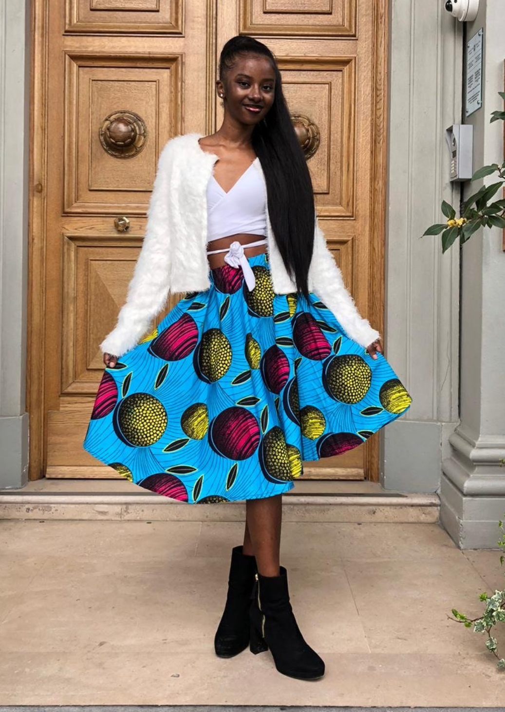 A light blue midi skirt with bold African print. The pleated midi skirt has pops of pink and yellow, making a statement African print dress.