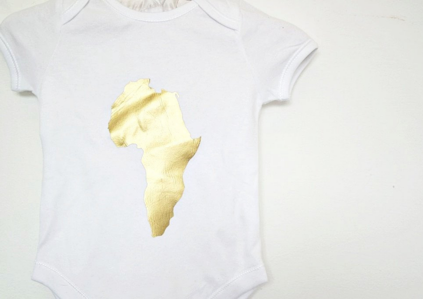 Baby bodysuit: This baby romper is a white short sleeve playsuit with gold map of Africa on the centre of the chest.